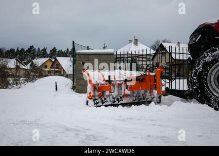 le tracteur rouge pelle la neige après une tempête de neige avec une charrue, vue rapprochée. Banque D'Images