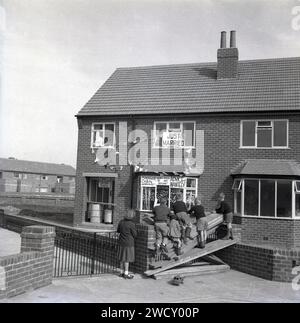 Années 1960, historique, juste marié.... sur un nouveau lotissement, les écoliers debout sur des planches de construction en bois barricadant l'allée d'une maison récemment construite, regardant les banderoles et les avis de mariage amusants qui décorent son extérieur. Les slogans amusants récemment mariés incluent : pas d'appelants après 18h30, cabane de snoggers - leçons!, New Weds - Do Not Disturb, Advice Wanted! Banque D'Images