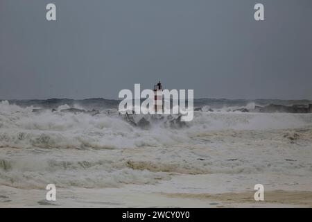 Povoa de Varzim quai d'entrée du port et balise inondés par les vagues de mer agitées, côte nord du portugal. Banque D'Images