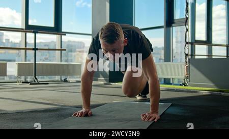 Entraîneur sportif caucasien faisant l'exercice d'alpinisme planche de course sur tapis de fitness homme athlète coureur pliant les genoux entraînement homme fort Banque D'Images