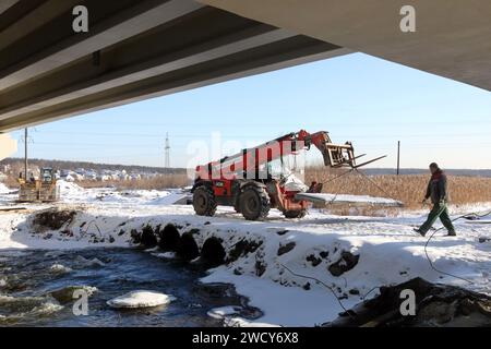 HOSTOMEL, UKRAINE - JANVIER 17, 2024 - des travaux de réparation sont en cours sur le pont de l'Hostome qui a été ruiné par l'armée ukrainienne qui a aidé à arrêter l'avance et à détruire une grande colonne de véhicules blindés russes essayant d'atteindre la capitale ukrainienne pendant la bataille de Kiev en février 2022, Hostomel, région de Kiev, nord de l'Ukraine. La circulation a été partiellement reprise le long du pont de 134 m de long sur la rivière Irpin à la périphérie d'Hostomel qui relie Bucha et Kiev. Banque D'Images