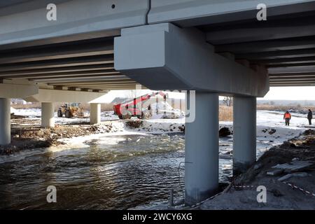 HOSTOMEL, UKRAINE - JANVIER 17, 2024 - des travaux de réparation sont en cours sur le pont de l'Hostome qui a été ruiné par l'armée ukrainienne qui a aidé à arrêter l'avance et à détruire une grande colonne de véhicules blindés russes essayant d'atteindre la capitale ukrainienne pendant la bataille de Kiev en février 2022, Hostomel, région de Kiev, nord de l'Ukraine. La circulation a été partiellement reprise le long du pont de 134 m de long sur la rivière Irpin à la périphérie d'Hostomel qui relie Bucha et Kiev. Banque D'Images