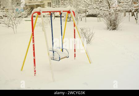 Balançoire pour enfants, recouverte d'une épaisse couche de neige après une forte chute de neige Banque D'Images