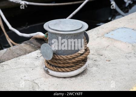 Poteau d'amarrage de quai métallique avec corde pour fixer des bateaux de pêche à proximité Banque D'Images