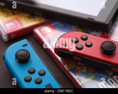 Tambov, Fédération de Russie - 17 janvier 2024 Une console Nintendo Switch avec des joy-cons détachés couchés sur des boîtes de jeu vidéo qui sont couchées sur un su noir Banque D'Images