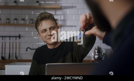 Homme barbu discutant de l'achat d'appartement avec l'agent immobilier à la réunion de bureau, serrant la main, obtenant les clés de son propre logement Banque D'Images