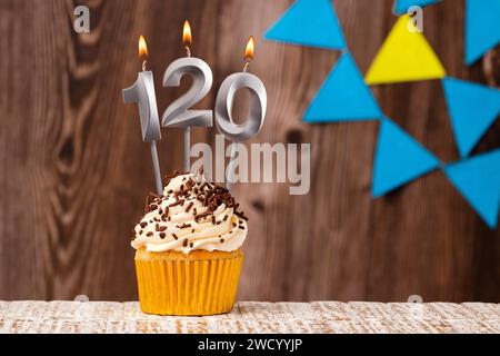 Bougie brûlante - numéro d'anniversaire 120 sur fond en bois avec fanions Banque D'Images