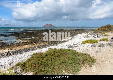 Vue de la côte volcanique rocheuse de Fuerteventura à Corralejo avec l'île de Lobos en arrière-plan Banque D'Images