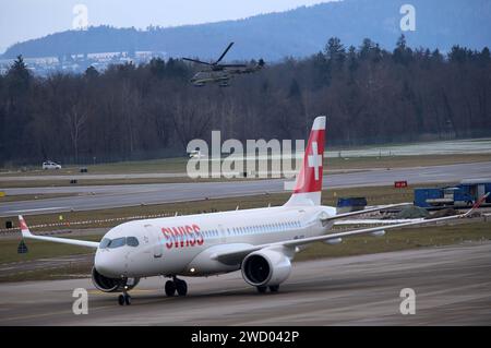 Ein Passagierflugzeug der Schweizer Fluggesellschaft Swiss vom Typ Airbus A220-300 mit der Registrierung HB-JCG auf dem Flughafen Zürich. Oben sichtbar ein Helikopter der Schweizer Luftwaffe vom Typ Super Puma.Der Helikopter ist Teil des Luftkonvois für den ukrinischen Präsidenten Wolodimir Selenski. Ein Passagierflugzeug der Schweizer Fluggesellschaft Swiss vom Typ Airbus A220-300 mit der Registrierung HB-JCG auf dem Flughafen Zürich. Oben sichtbar ein Helikopter der Schweizer Luftwaffe vom Typ Super Puma.Der Helikopter ist Teil des Luftkonvois für den ukrinischen Präsidenten Wolodimir Sele Banque D'Images