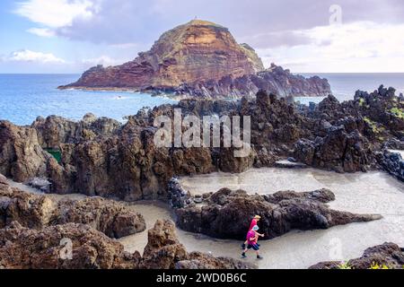 Paysage marin rocheux, deux touristes marchant par l'océan à Porto Moniz côte nord avec des formations de lave naturelles, côte de l'île de Madère, Portugal Banque D'Images