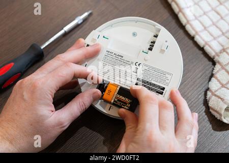 Remplacement de la pile alcaline de secours dans une alarme de chaleur alimentée par secteur EI 144RC (alarme incendie) dans une cuisine après qu'elle a commencé à émettre un bip à partir d'une faible puissance. ROYAUME-UNI Banque D'Images