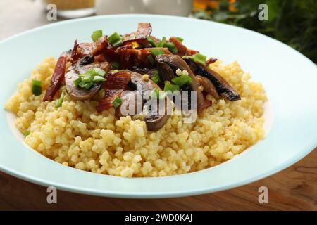 Savoureux porridge de millet avec champignons, bacon et oignon vert sur la table, gros plan Banque D'Images