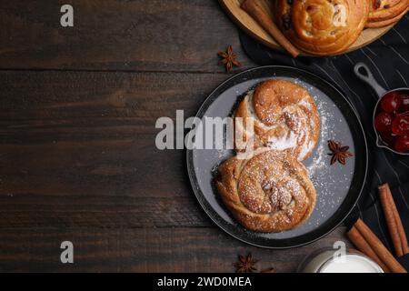 Délicieux petits pains avec de la poudre de sucre, des baies et des épices sur la table en bois, plat avec espace pour le texte. Petits pains sucrés Banque D'Images