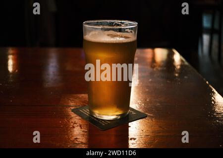 Une pinte de bière sur une table dans une pièce sombre Banque D'Images
