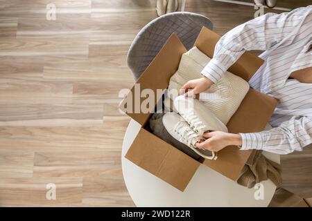 Femme emballant des vêtements et des chaussures dans la boîte en carton saisonnier rangement confortable organiser la vue de dessus Banque D'Images