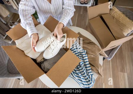 Femme emballant des vêtements et des chaussures dans la boîte en carton saisonnier rangement confortable organiser la vue de dessus Banque D'Images