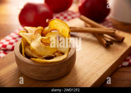Croustilles de pommes maison, fines tranches de pomme déshydratées et cuites au four, saupoudrées de cannelle en poudre, recette facile pour une collation saine. Banque D'Images