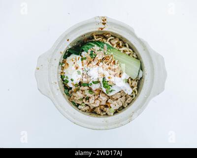 Bakmi avec des compliments supplémentaires comme l'œuf, pok choy, poireaux et oignons frits sur le bol de service vintage sur fond blanc Banque D'Images