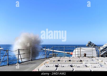 Le croiseur de missiles guidés USS Hue City tire un canon Mark 45 5 pouces. Banque D'Images