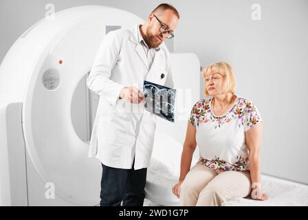 Tomodensitométrie médicale ou scanner IRM. Patient faisant l'IRM, médecin tenant et expliquant les résultats. Femme assise sur le canapé. Concept de médecine et de santé. Banque D'Images