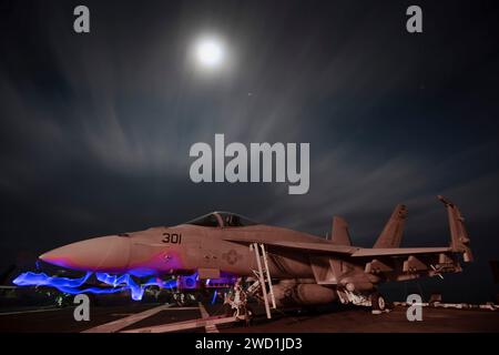 Un F/A-18E Super Hornet sur le pont d'envol à bord de l'USS John C. Stennis la nuit. Banque D'Images