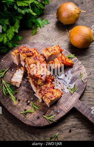 Ventre de porc grillé avec peau croustillante, avec oignon et herbes sur fond de bois Banque D'Images