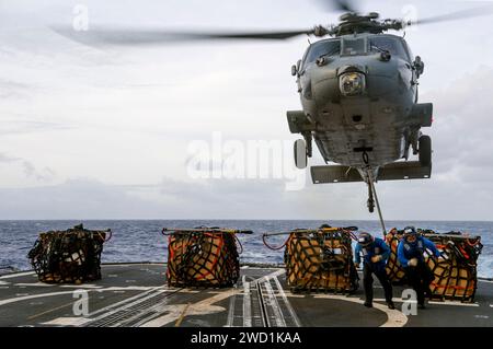 Des marins relient des cargaisons à un hélicoptère MH-60S Sea Hawk sur le pont d'envol de l'USS Lake Champlain. Banque D'Images