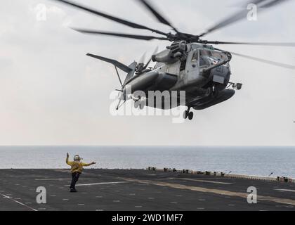 Aviation Boatswain's Mate signale qu'un CH-53E Super Stallion décolle de l'île de l'USS Makin. Banque D'Images