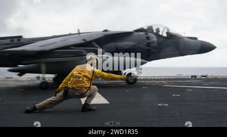 Aviation Boatswain's Mate signale à un AV-8B Harrier lorsqu'il se lance depuis le pont d'envol de l'USS Bonhomme Richard. Banque D'Images