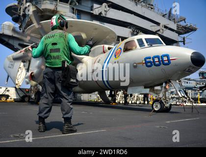 Aviation Structural Mechanic dirige un E-2D Hawkeye sur le pont d'envol de l'USS Nimitz. Banque D'Images