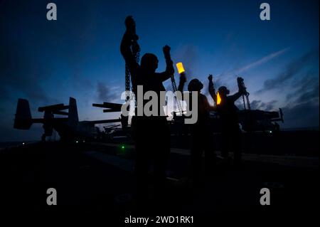 Les compagnons de Boatswain d'aviation présentent des cales et des chaînes au pilote d'un hélicoptère CH-53E Super Stallion. Banque D'Images