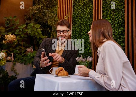Jeune homme et femme parlant à l'aide d'un téléphone portable ayant une réunion d'affaires dans un café Banque D'Images