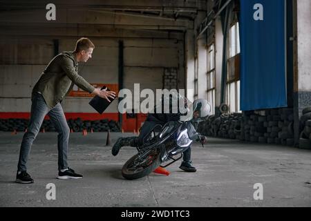 Élève tombant de moto à la classe de formation en auto-école Banque D'Images