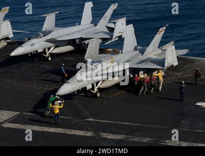 Les marins et les Marines américains effectuent une poussée en arrière sur un F/A-18C Hornet sur le pont d'envol de l'USS Nimitz. Banque D'Images