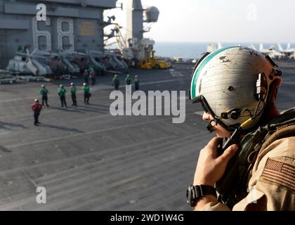 L'avionneur de l'US Navy regarde un hélicoptère MH-60S Sea Hawk alors qu'il décolle du pont d'envol de l'USS Nmitz. Banque D'Images