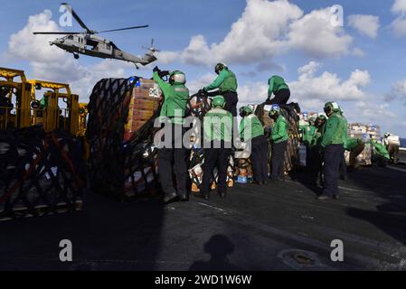 Les marins et les Marines américains préparent la cargaison pour le transport sur le pont d'envol de l'USS Theodore Roosevelt. Banque D'Images