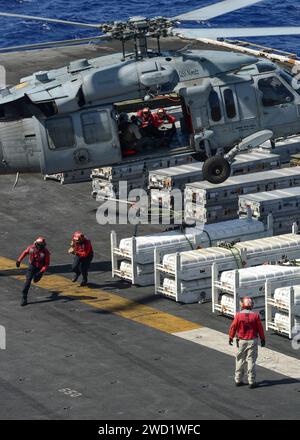 Les marins courent vers la zone de sécurité après avoir chargé un hélicoptère MH-60S Sea Hawk avec du matériel à bord de l'USS Nimitz. Banque D'Images