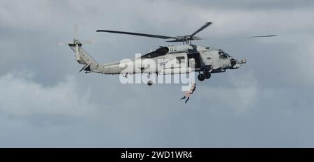 Des marins font la démonstration des opérations de sauvetage de nageurs à partir d'un hélicoptère MH-60R Sea Hawk. Banque D'Images