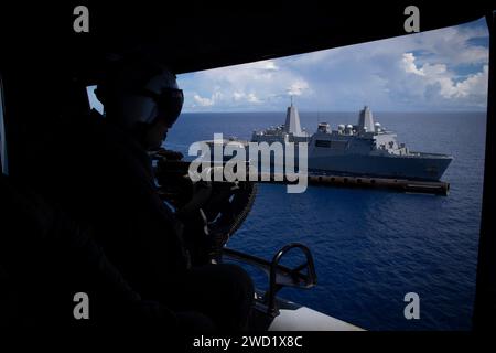 Un Marine américain regarde par la porte d'un hélicoptère UH-1Y Huey à l'USS New Orleans. Banque D'Images