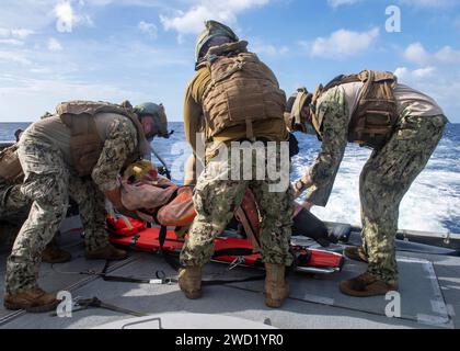 Les marins préparent une victime simulée pour le transport en hélicoptère sur un patrouilleur Mark VI. Banque D'Images