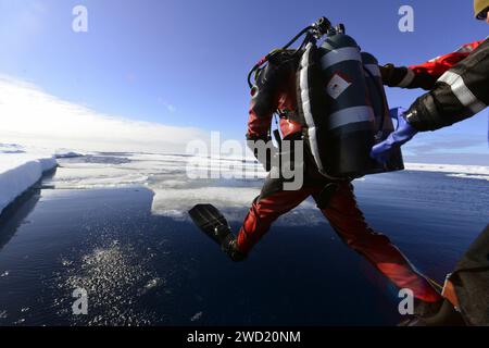 Le plongeur de la Garde côtière entre dans l'eau à partir d'un petit bateau Cutter Healy de la Garde côtière dans l'Arctique. Banque D'Images