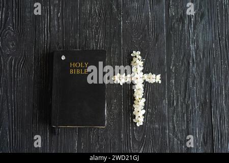 Fleurs printanières en forme de croix avec une bible sur un vieux fond de bois. Banque D'Images