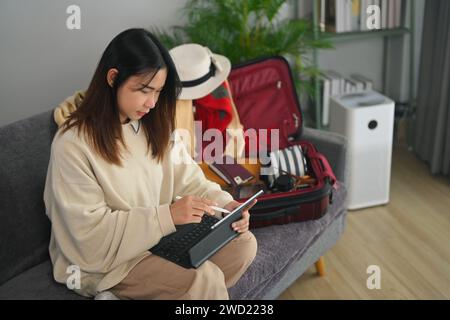 Heureuse jeune femme lisant le blog touristique en ligne ou réservant des billets ou une chambre d'hôtel sur ordinateur portable Banque D'Images