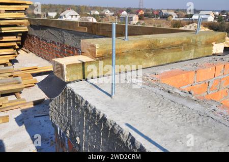 Début de la construction de toiture de la maison en montant les fermes, les poutres de toit en bois au bord du mur. Banque D'Images