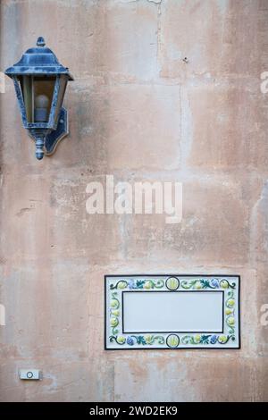 Panneau traditionnel maltais de signe de maison peint sur des carreaux de céramique placés sur le mur de pierre sans texte à l'intérieur. Banque D'Images