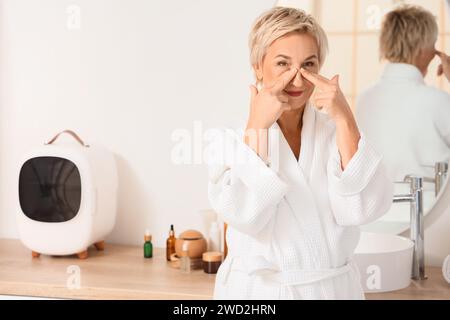 Femme mature faisant un exercice de bâtiment de visage dans la salle de bains Banque D'Images