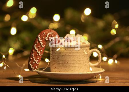 Tasse de cacao chaud avec biscuit de pain d'épice, guimauves et décor de Noël sur la table en bois sur fond flou Banque D'Images