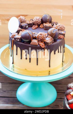 Gâteau au chocolat décoré de truffes, bonbons, biscuits, noix de pécan avec chocolat fondu et caramel salé sur le dessus Banque D'Images