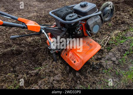 Une technologie agricole de pointe en jeu : le cultivateur labour méticuleusement le sol intact, préparant le terrain pour des récoltes abondantes. Banque D'Images