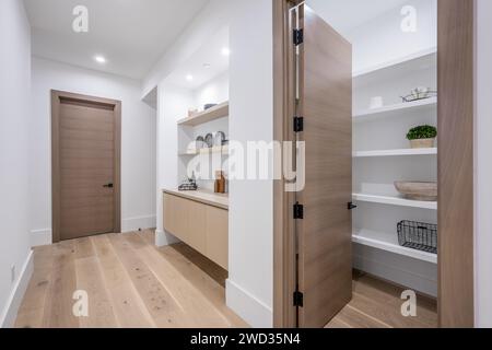 Un couloir spacieux et bien éclairé avec parquet élégant et étagères soigneusement disposées affichant une pléthore d'objets organisés Banque D'Images